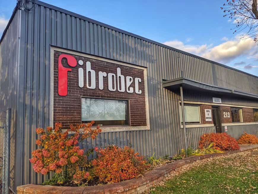 Exterior of an industrial building with a Fibrobec sign and autumn foliage