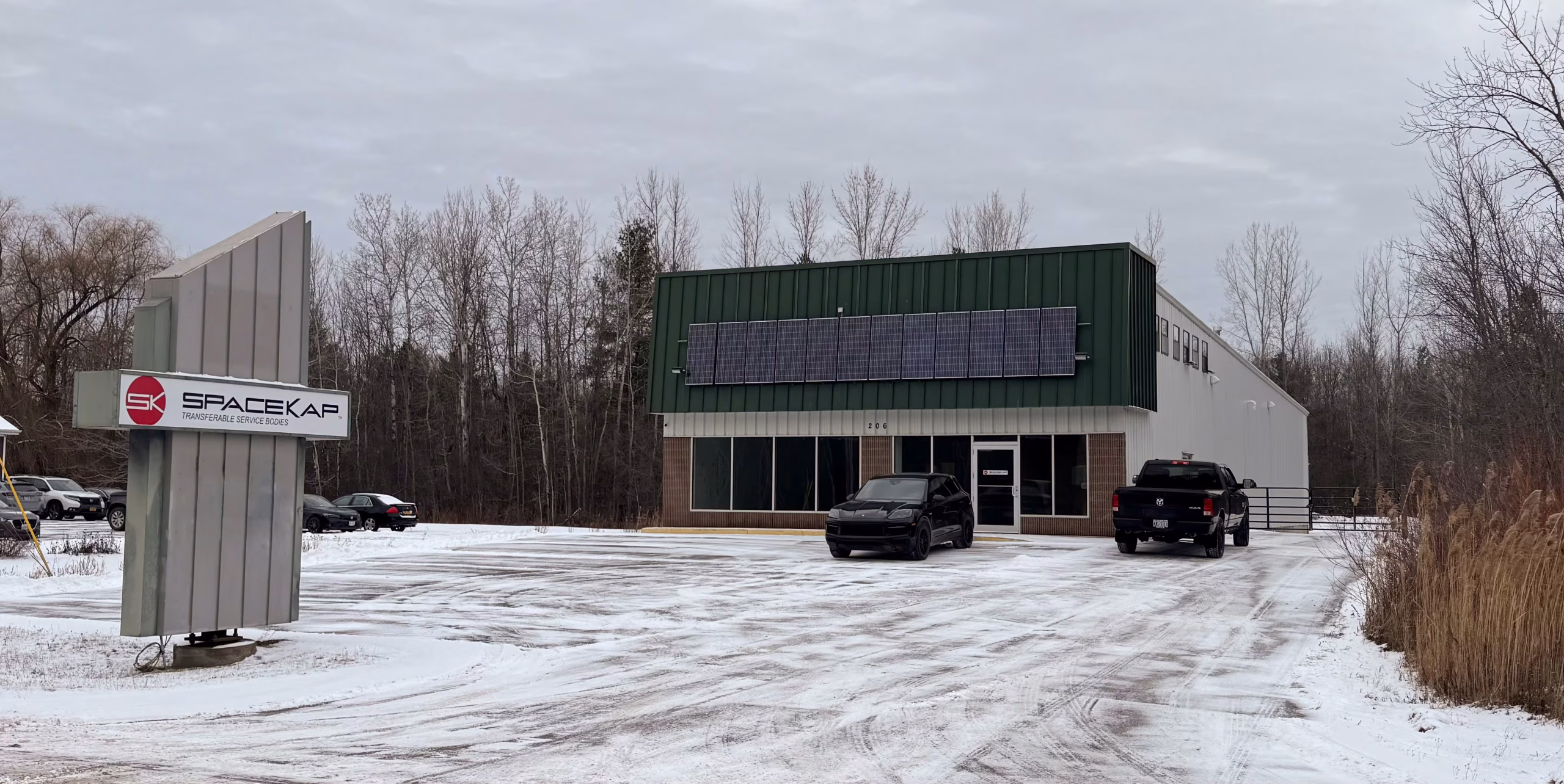 Commercial building with solar panels on the facade and parking lot covered in snow with cars