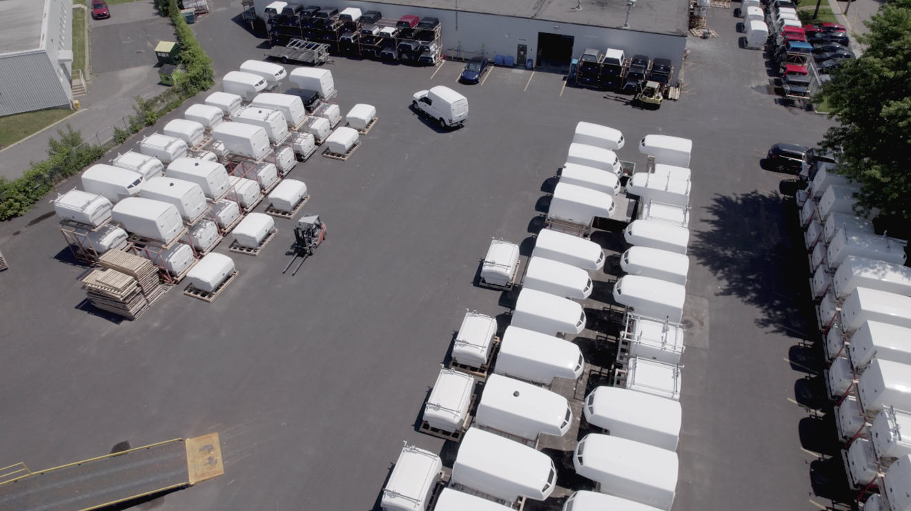 Aerial view of multiple white fiberglass truck caps and a forklift in an industrial yard