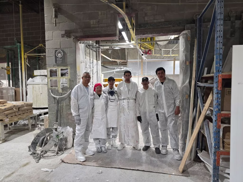 Groupe de six travailleurs en tenue blanche de protection dans un atelier de fabrication industrielle
